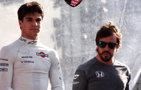 Lance Stroll (left) stands next to his much more talented teammate Fernando Alonso (right).