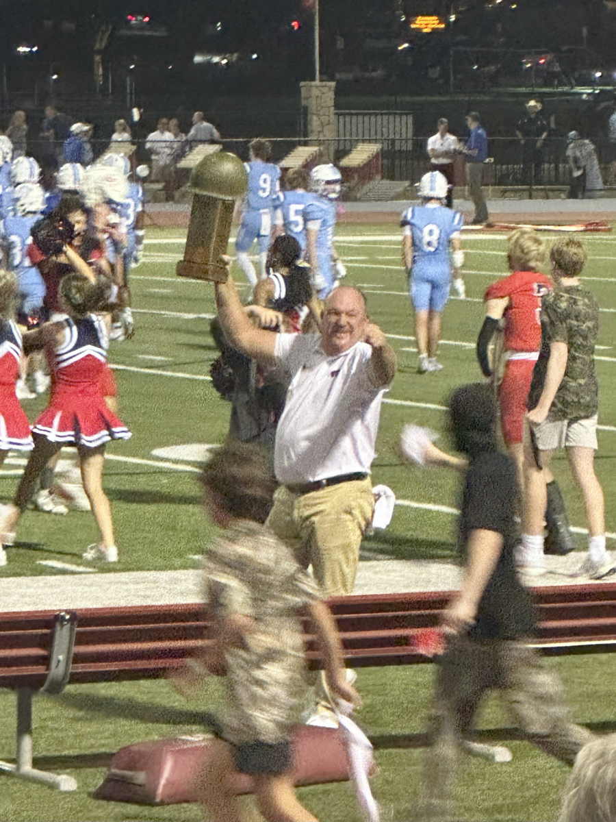 Varsity Football Head Coach Keith Burns hoisting the Battle of Bryant Irvin trophy after the game