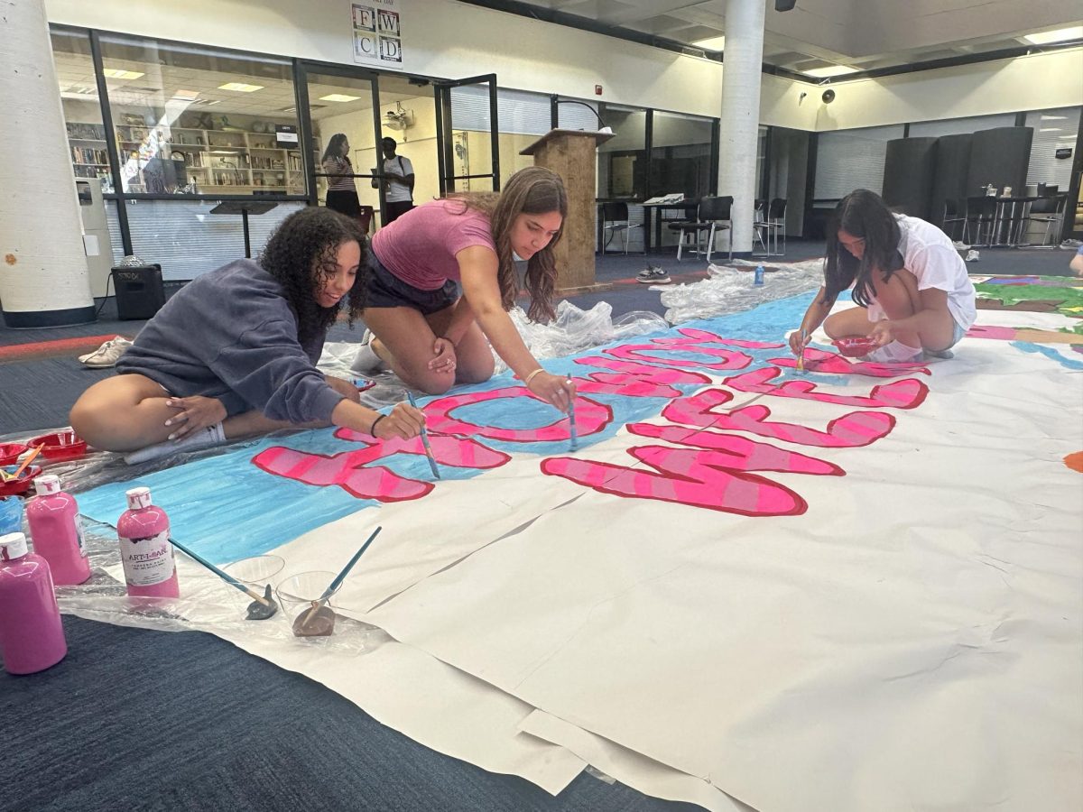 Bella Rugema '27, Martha Wynn Senter '27, and Cecily Ozaeta '27 painting a banner.