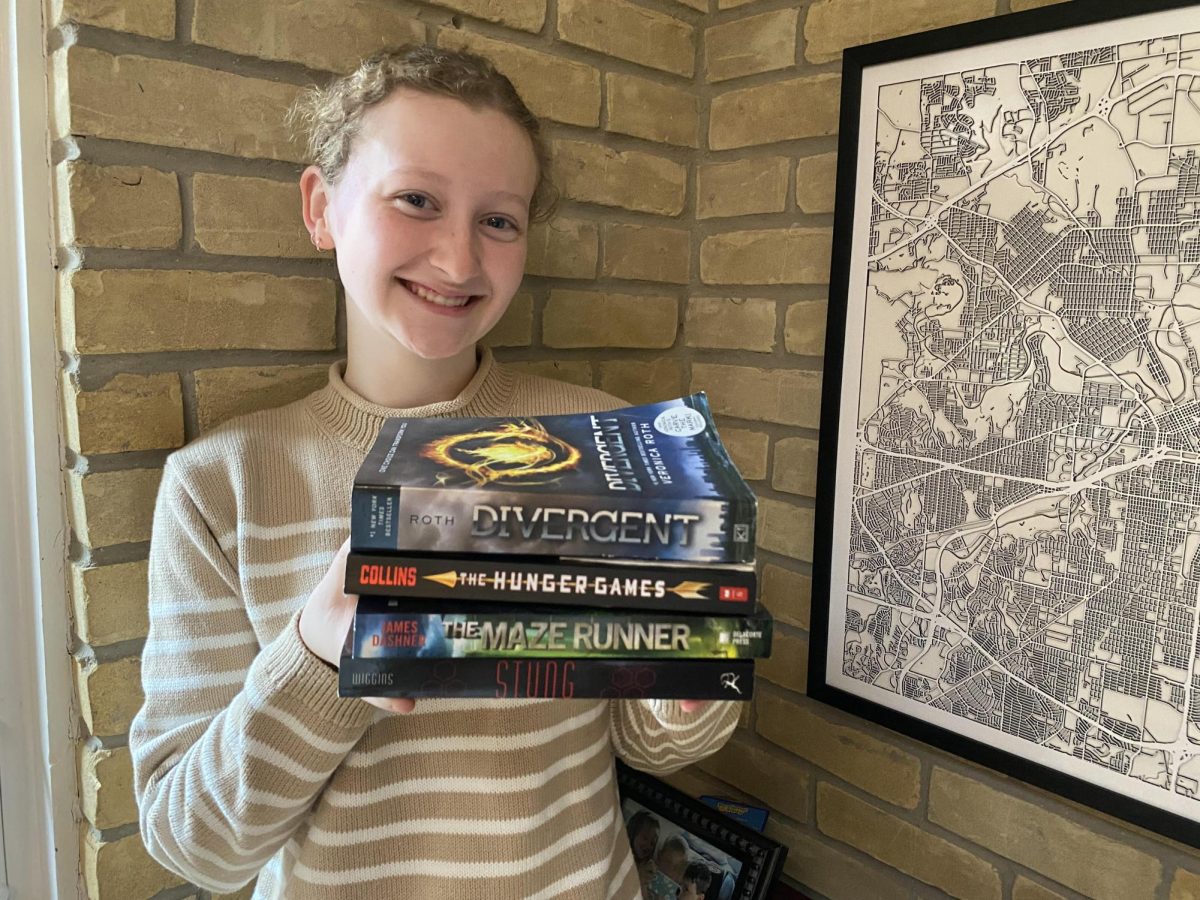 Evie Blan '27  holding her favorite dystopian books.